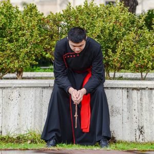 Sacerdote sentado rezando el Rosario
